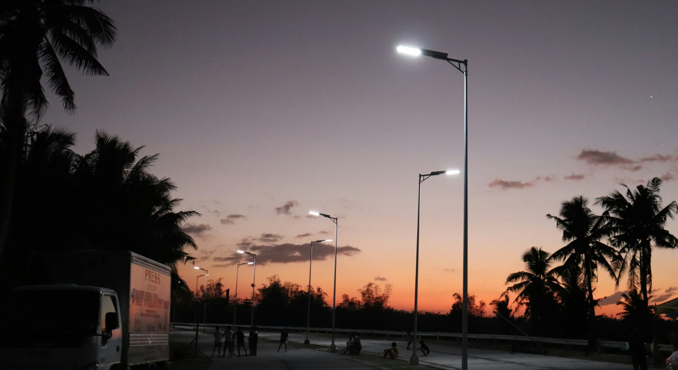 Solar street lights illuminating a roadway at dusk